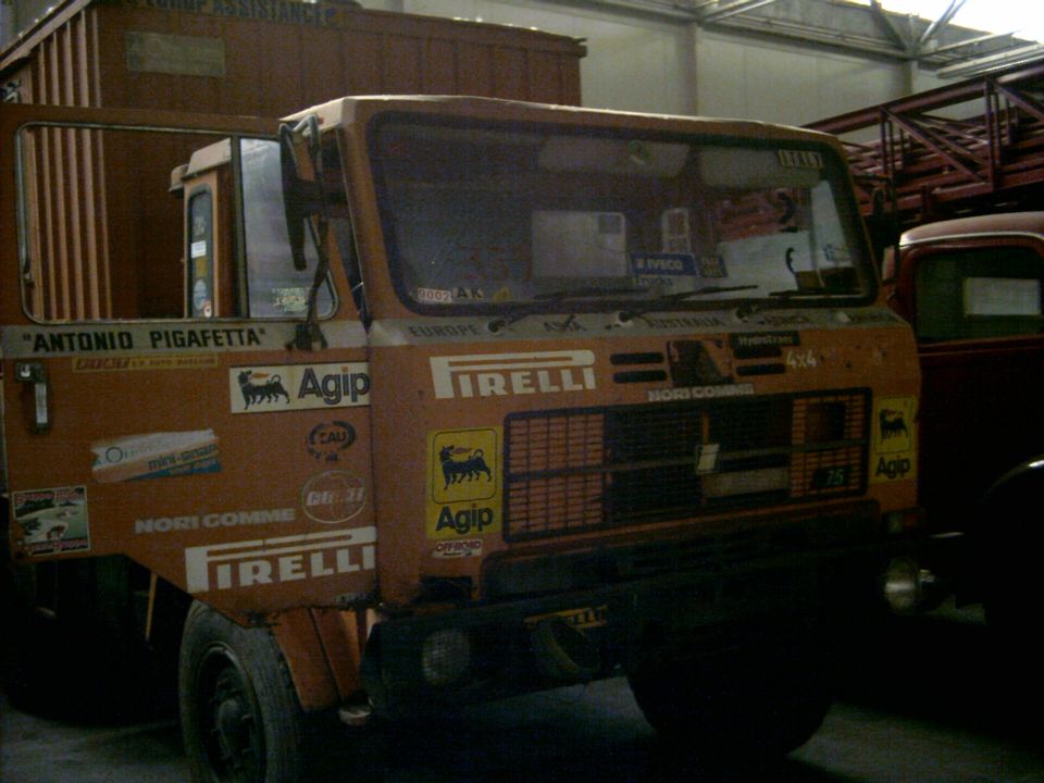 Camion Iveco arancione con le scritte del giro del mondo in officina